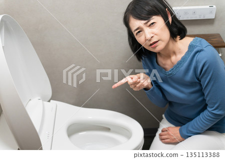 Middle-aged woman having trouble with toilet trouble Lifestyle image Middle-aged woman having trouble with toilet trouble Lifestyle image 135113388