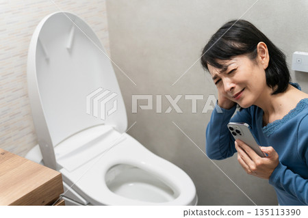Middle-aged woman having trouble with toilet trouble Lifestyle image Middle-aged woman having trouble with toilet trouble Lifestyle image 135113390