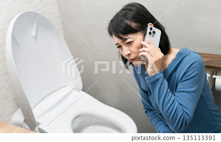 Middle-aged woman having trouble with toilet trouble Lifestyle image 135113391