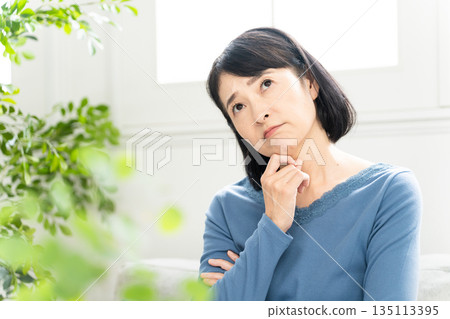 Middle-aged woman sitting on the sofa Lifestyle image Middle-aged woman sitting on the sofa Lifestyle image 135113395