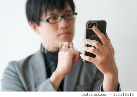 Man with glasses holding a smartphone 135116116