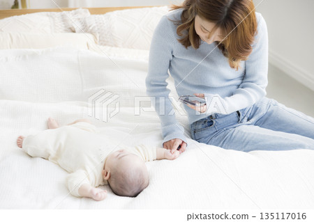 一位年輕的母親正在用智慧型手機為她的寶寶拍照。 一位年輕的母親正在用智慧型手機為她的寶寶拍照。 135117016