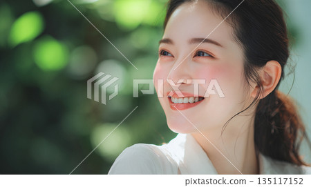 一位面帶自然微笑、肌膚光滑的女子，在綠色背景下的肖像照。美人照片。 135117152