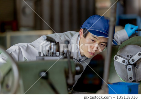 一名男工人在工廠操作機器 一名男工人在工廠操作機器 135118316