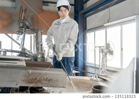 Male worker working in an aluminum melting furnace at a factory Male worker working in an aluminum melting furnace at a factory 135118323