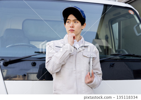 A delivery staff member worried in front of a truck 135118334