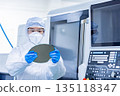Worker in protective suit holding silicon wafer in factory 135118347