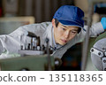 Male worker operating a machine in a factory 135118365