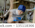 Male worker operating a machine in a factory 135118366