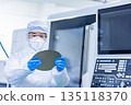 Worker in protective suit holding silicon wafer in factory 135118370