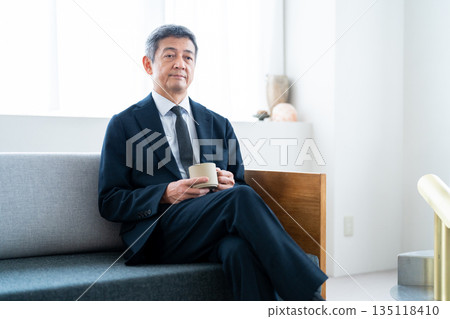 Businessman relaxing on a hotel sofa drinking coffee 135118410