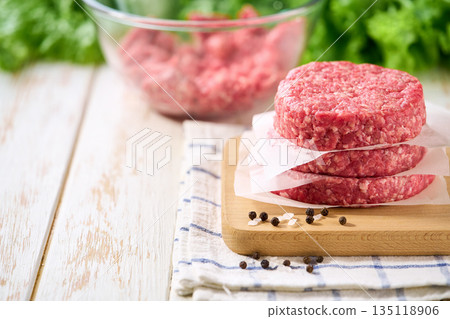 Stack of raw burger beef patties on a white table, selective focus. Natural meat product. Stack of raw burger beef patties on a white table, selective focus. Natural meat product. 135118906