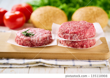 Raw ground beef burger patties separated by parchment paper on a white table, selective focus. Raw ground beef burger patties separated by parchment paper on a white table, selective focus. 135118908