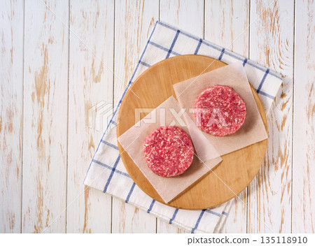 Raw minced beef patties for burgers on a white table, top view. Raw minced beef patties for burgers on a white table, top view. 135118910