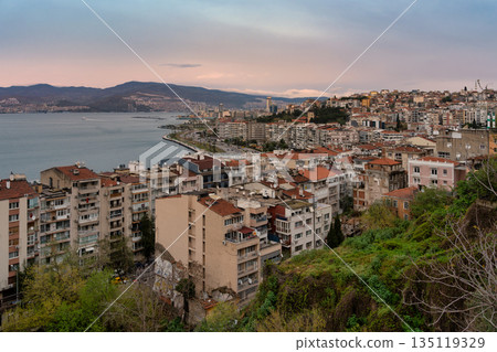 Izmir, Turkey: Dusk panorama of the Gulf of Izmir and city, featuring coastal road, residential buildings, and mountains. Izmir, Turkey: Dusk panorama of the Gulf of Izmir and city, featuring coastal road, residential buildings, and mountains. 135119329