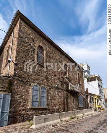 Bet Israel Synagogue, a historic stone building on a cobbled street in Izmir, Turkey, under a blue sky. Bet Israel Synagogue, a historic stone building on a cobbled street in Izmir, Turkey, under a blue sky. 135119330