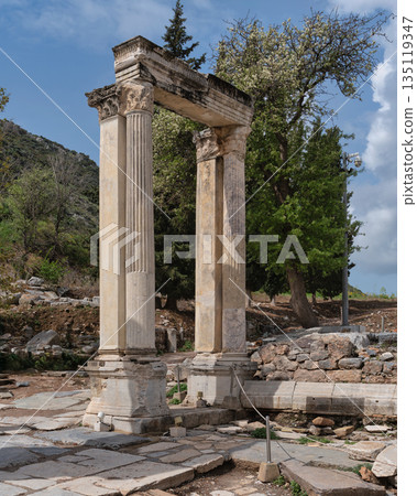 Hadrian's Gate, ancient Roman ruins in Ephesus, Selcuk, Turkey, under a blue sky with blooming trees. 135119347