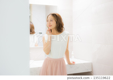 Young woman looking at a mirror 135119622