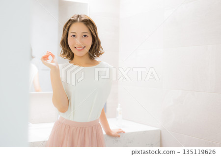 Young woman looking at a mirror 135119626
