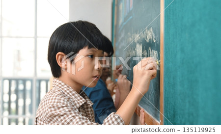 Side view of asian boy writing engineering prompt with girl. Close up. Pedagogy. 135119925