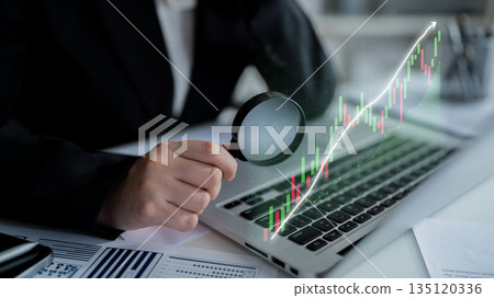 Businessperson analyzing financial data on laptop with magnifying glass to understand market trends and stock performance in contemporary office environment Impute Businessperson analyzing financial data on laptop with magnifying glass to understand market trends and stock performance in contemporary office environment Impute 135120336