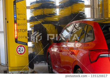 Red car inside a car wash tunnel, concept of vehicle maintenance and cleaning service. 135120817