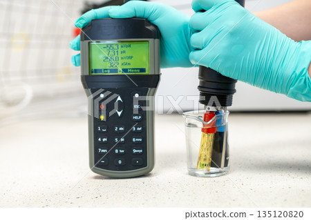 Woman hand in glove measuring pH of water. Woman hand in glove measuring pH of water. 135120820