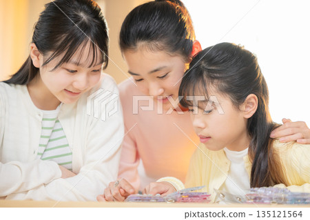 Elementary school girls enjoying exchanging stickers using a sticker book after school Elementary school girls enjoying exchanging stickers using a sticker book after school 135121564