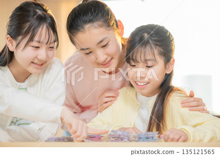 Elementary school girls enjoying exchanging stickers using a sticker book after school Elementary school girls enjoying exchanging stickers using a sticker book after school 135121565