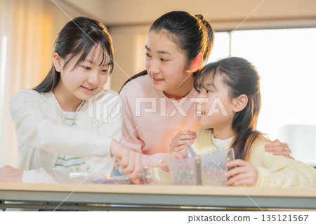 Elementary school girls enjoying exchanging stickers using a sticker book after school 135121567