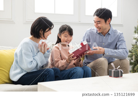 Elementary school girl happy to receive Christmas present from her parents Elementary school girl happy to receive Christmas present from her parents 135121699