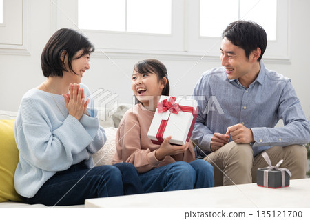 小學生女孩很高興收到父母送的聖誕禮物 小學生女孩很高興收到父母送的聖誕禮物 135121700