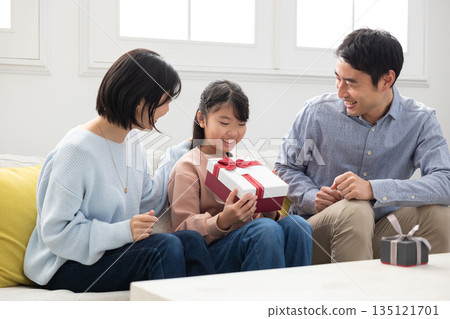 小學生女孩很高興收到父母送的聖誕禮物 小學生女孩很高興收到父母送的聖誕禮物 135121701
