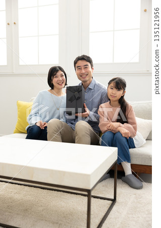 一家三口：父親、妻子和女兒，手裡拿著妻子和女兒送的禮物，臉上都洋溢著笑容。 135121956