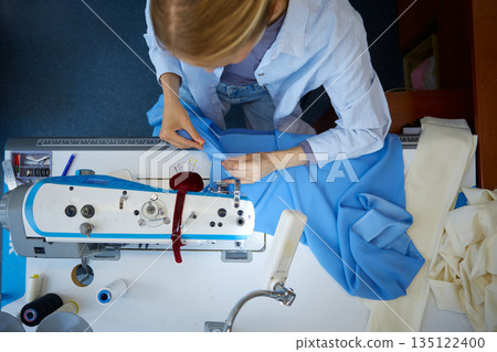 Expert seamstress crafting detailed blue textiles Expert seamstress crafting detailed blue textiles 135122400