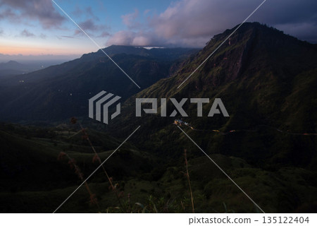 A stunning view of a mountain range in Sri Lanka under the night sky, bathed in the soft glow of the moon. A stunning view of a mountain range in Sri Lanka under the night sky, bathed in the soft glow of the moon. 135122404