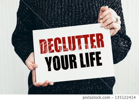Girl holding a card with text DECLUTTER YOUR LIFE. 135122414