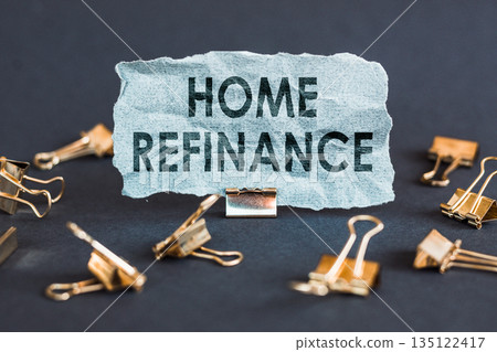 A scrap of blue paper with clips on a gray background with the text - HOME REFINANCE. A scrap of blue paper with clips on a gray background with the text - HOME REFINANCE. 135122417