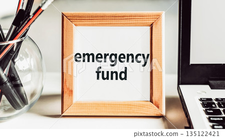 "Emergency fund" text in a wooden frame on an office table. Financial concept. 135122421