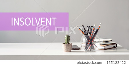 Text INSOLVENT is written on a folder lying on a stack of papers with a pen on the table. Business concept 135122422