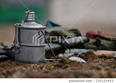 Military equipment: boots, bowler hat, canned food, belt and mug. soldier's lunch in nature 135122433