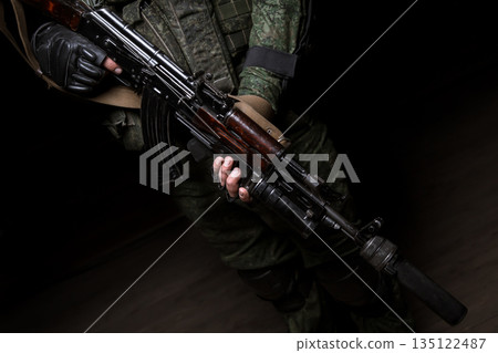 Closeup photo shoot of man's hand holding machine gun. Man is wearing military uniform and wach. Closeup photo shoot of man's hand holding machine gun. Man is wearing military uniform and wach. 135122487