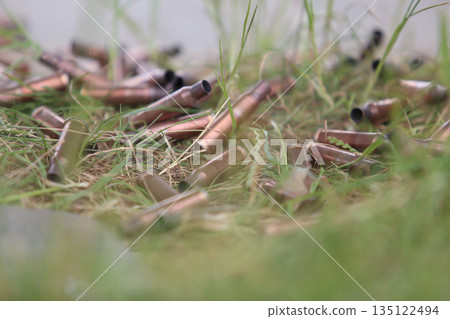 bullet shells ground. Cases of bullets lying on the floor of artificial grass 135122494