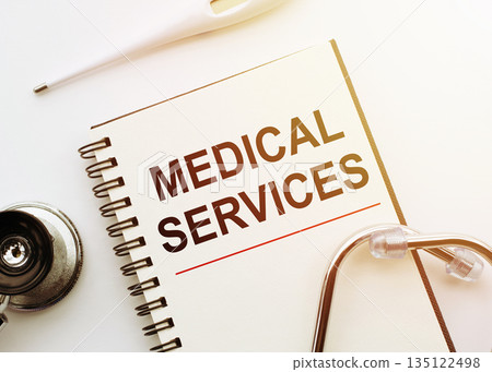 Notebook with text MEDICAL SERVICE on white desk with stethoscope and thermometer. Medical concept. Notebook with text MEDICAL SERVICE on white desk with stethoscope and thermometer. Medical concept. 135122498