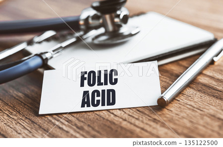 FOLIC ACID text written on card on wooden table with medical background. FOLIC ACID text written on card on wooden table with medical background. 135122500