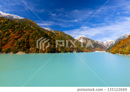 長野縣大町市平良－高瀨水壩調節湖的秋葉呈現出鮮豔的乳藍色，遠處是白雪皚皚的山峰，映襯著蔚藍的天空。 135122689