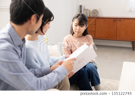 Elementary school girl showing her report card to her parents 135122745