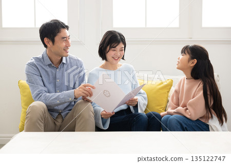 Elementary school girl showing her report card to her parents Elementary school girl showing her report card to her parents 135122747