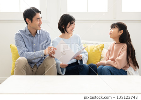 Elementary school girl showing her report card to her parents Elementary school girl showing her report card to her parents 135122748