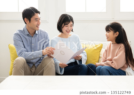 Elementary school girl showing her report card to her parents Elementary school girl showing her report card to her parents 135122749